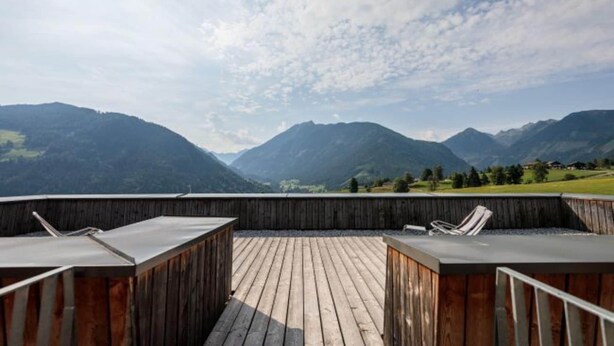 A wooden deck with two lounge chairs and a table, overlooking a mountainous landscape. - Lush apartment with private sauna (Schladming - Rohrmoos)