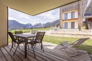 Een houten terras met een tafel en stoelen, met uitzicht op een bergachtig landschap.
