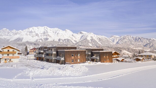A snow-covered mountain resort with modern wooden buildings and a clear view of the mountains. - Apartment with roof terrace (Schladming - Rohrmoos)