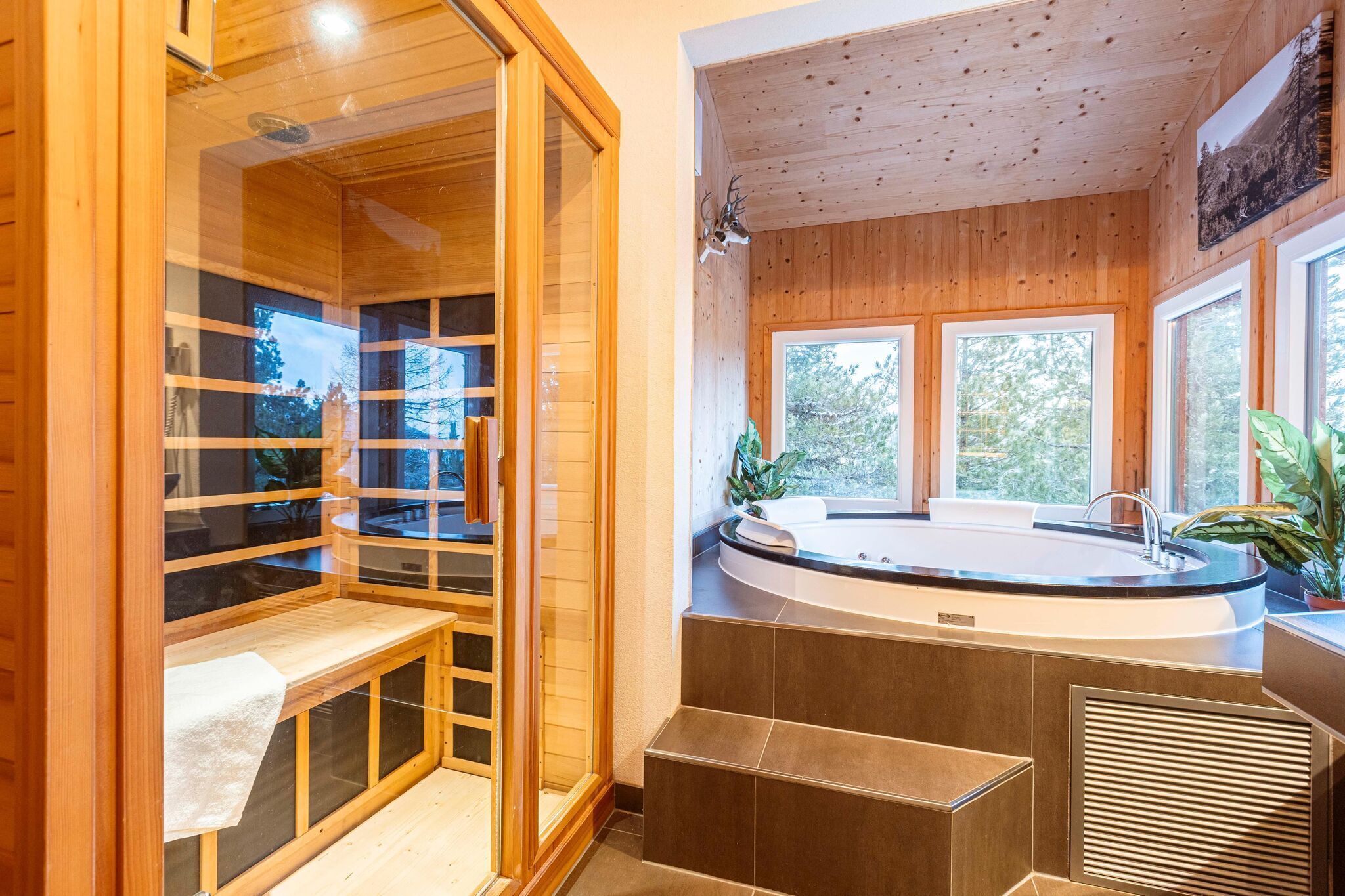 A modern spa room with a wooden interior, a hot tub, and large windows offering a view of the outdoors.