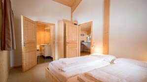 A wooden room with two beds, a bathroom, and a kitchenette.