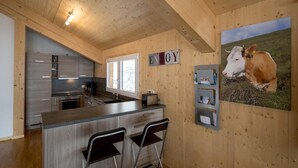 A modern kitchen with wooden walls, a bar area, and a cow painting.