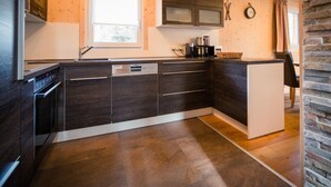 Uma cozinha moderna com armários de madeira escura, lava-louças embutida e uma janela ampla que traz luz natural.
