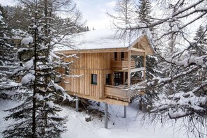 A wooden cabin with a balcony, surrounded by snow-covered trees.