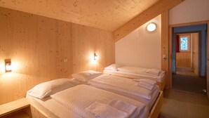Ein Zimmer in einer Holzhütte mit zwei Betten, einem Nachttisch und einer an der Wand befestigten Leuchte.