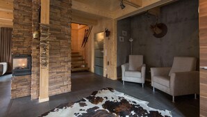 A cozy living room with a stone fireplace, a large rug, and two armchairs.