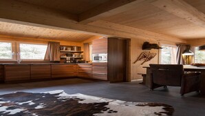 A modern kitchen with wooden cabinets, a microwave, and a dining area with a table and chairs.