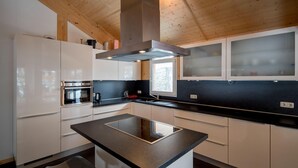 A modern kitchen with white cabinets, a black countertop, and a stainless steel range hood. - Lovely chalet with sauna (Turracherhöhe)