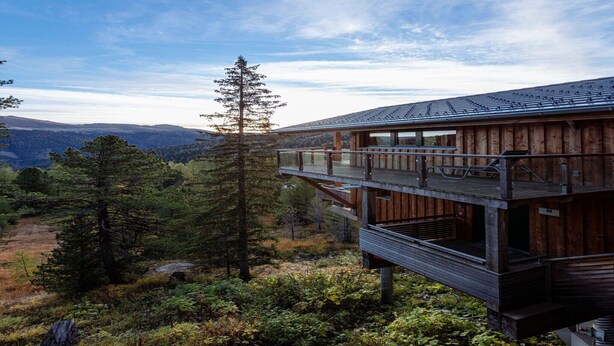 A wooden cabin with a balcony overlooking a forested landscape. - Lovely chalet with sauna (Turracherhöhe)