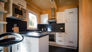 Une cuisine moderne avec des meubles blancs, un plan de travail noir, des appareils électroménagers en acier inoxydable et une fenêtre qui laisse entrer la lumière naturelle.