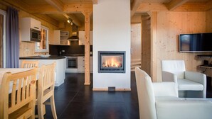 A modern living room with a fireplace, wooden furniture, and a flat-screen TV. - Charming chalet with indoor hot tub (Turracherhöhe)