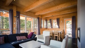 A wooden interior with a sofa, chairs, a table, and large windows. - Charming chalet with indoor hot tub (Turracherhöhe)