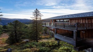 A wooden cabin with a balcony overlooking a forested landscape. - Charming chalet with indoor hot tub (Turracherhöhe)