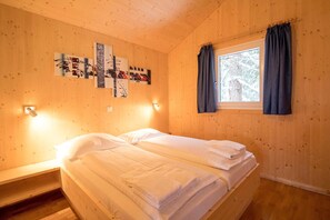 A wooden cabin room with two beds, a window with curtains, and wall-mounted artwork. - Chalet in Austria near Ski Lift (Turracherhöhe)