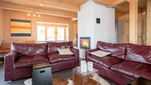 A cozy living room with two leather sofas, a fireplace, and a clear coffee table. - Chalet in Austria near Ski Resort (Turracherhöhe)