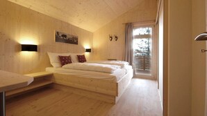 Une chambre avec des murs en bois, un lit, des lampes de chevet, une fenêtre avec des rideaux et un plafond en bois.