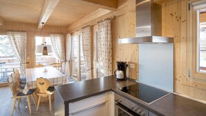 L’intérieur d’un chalet en bois comprend un coin cuisine équipé d’une cuisinière, d’un four et d’une machine à café.