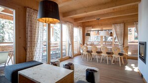L’intérieur d’un chalet chaleureux, avec une table à manger en bois, des chaises et un canapé.