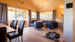 A wooden interior with a dining area, sofas, and a fur rug. - Chalet in Alps near Ski Slopes & Sauna (Turracherhöhe)