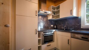 A modern kitchen with white cabinetry, a built-in oven, and a dishwasher. - Amazing chalet with infrared sauna (Turracherhöhe)