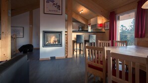 Un acogedor interior de cabaña con chimenea, una mesa de comedor de madera y sillas.