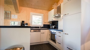 A modern kitchen with white cabinets, a built-in oven, and a microwave. - Cosy chalet with infrared sauna (Turracherhöhe)