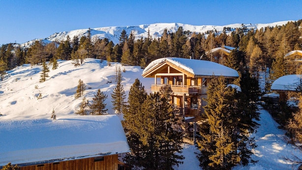 A wooden chalet with a balcony, surrounded by snow-covered trees and mountains in the background. - Cosy chalet with infrared sauna (Turracherhöhe)