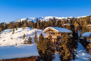A wooden chalet with a balcony, surrounded by snow-covered trees and mountains in the background. - Cosy chalet with infrared sauna (Turracherhöhe)