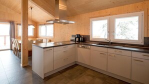 Ett modernt kök med träinredning, en köksö och ett stort fönster som släpper in naturligt ljus.