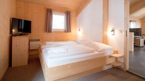 Ett rum med träpanel, en säng, en tv och ett litet pentry.