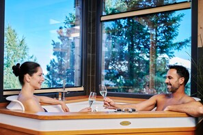 A couple in a modern hot tub with a large window view of trees. - Lovely Chalet in Turracherhöhe with Sauna (Turracherhöhe)