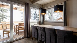 A modern dining area with a wooden table and chairs, large windows with curtains, and a hanging light fixture. - Lovely Chalet in Turracherhöhe with Sauna (Turracherhöhe)