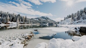 A winter landscape with a frozen lake, snow-covered trees, and mountains in the background. - Apartment in Pine Forest near Ski Slopes (Turracherhöhe)