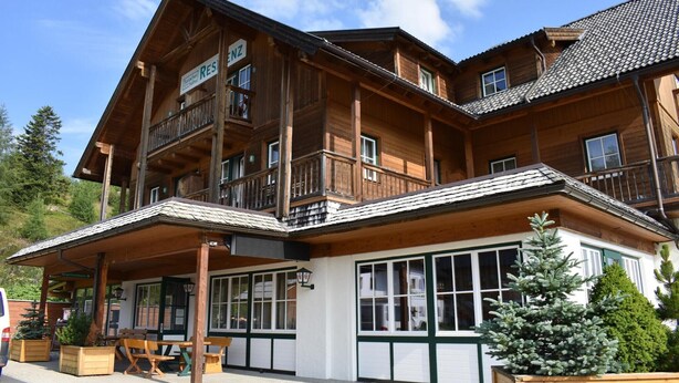 A wooden chalet with balconies, large windows, and a covered outdoor seating area. - Apartment in Pine Forest near Ski Slopes (Turracherhöhe)