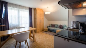 A compact living space with a dining area, kitchenette, and a sofa. - Apartment in Pine Forest near Ski Slopes (Turracherhöhe)
