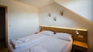 A twin bed with a wooden headboard, a bedside table, and a wall-mounted lamp.