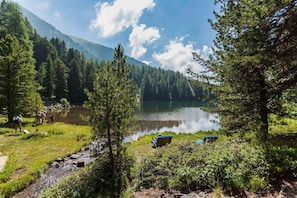 A serene lakeside setting with a wooden deck, a bench, and a small boat. - Premium chalet with infrared sauna (Turracherhöhe)