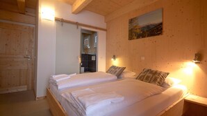 Ein Schlafzimmer mit Holzwänden, zwei Betten, einem Bild an der Wand und einer Tür zu einem Badezimmer.