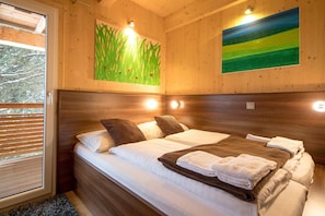 A wooden cabin room with a bed, pillows, and towels.