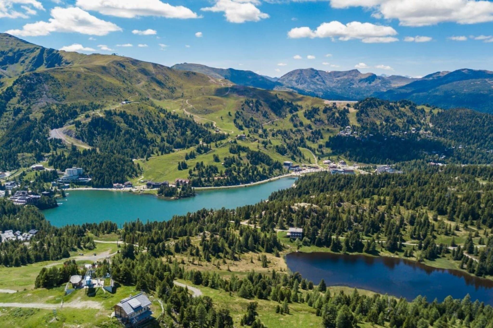 A mountainous landscape with a lake, buildings, and a road.