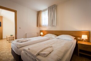 A double bed with white linens, a wooden headboard, two bedside tables with lamps, and a window with curtains. - Apartment in Alps near Ski Slopes (Turracherhöhe)