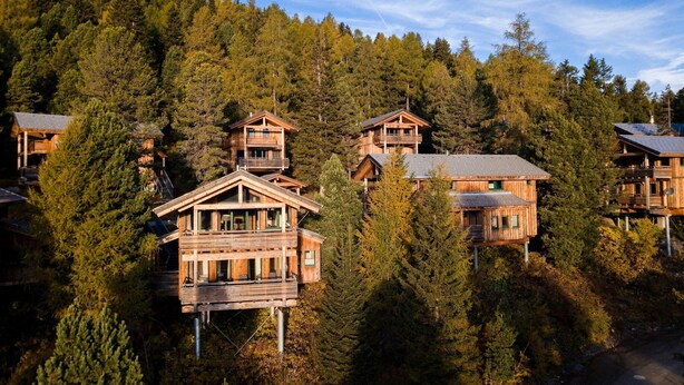 A cluster of wooden cabins on a hillside with a forest backdrop. - Modern cottage with whirlpool (Turracherhöhe)