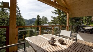 A wooden deck with a table and chairs, overlooking a mountainous landscape. - Modern cottage with whirlpool (Turracherhöhe)