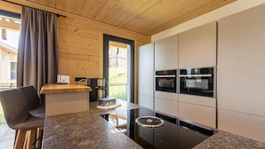 A modern kitchen with a built-in stove, a coffee machine, and a view of the outdoors.