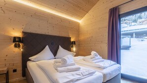 A wooden-paneled room with two beds, each with neatly folded white towels.