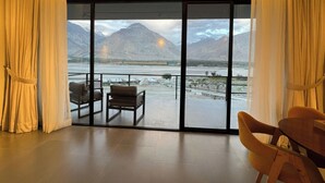 A modern room with a large sliding glass door leading to an outdoor terrace. Inside, there are two chairs and a small table. - Himmel Skardu by Luxus (Wazirpur)