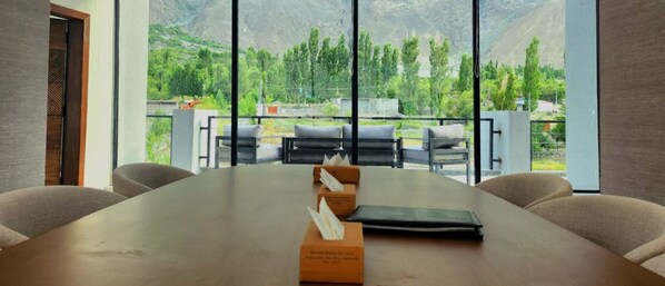 Une salle de conférence dotée d’une grande table, de chaises et offrant une vue sur un paysage montagneux grâce à de larges fenêtres.