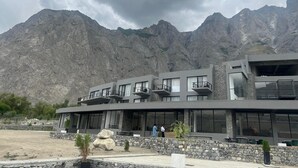 A modern building with large windows and balconies, set against a mountainous backdrop. - Himmel Skardu by Luxus (Wazirpur)