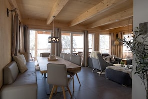 A spacious living area with a wooden ceiling, a dining table, and a sofa.