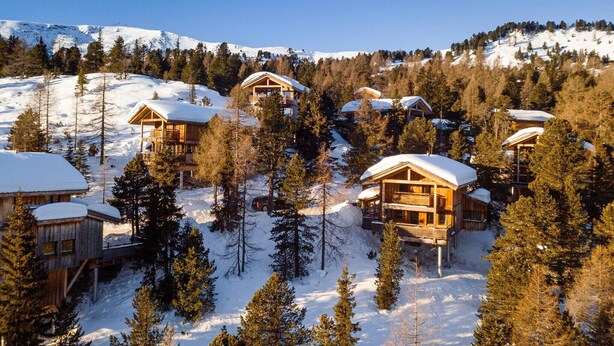 A cluster of wooden cabins surrounded by snow-covered trees and mountains. - Appealing chalet with infrared sauna (Turracherhöhe)